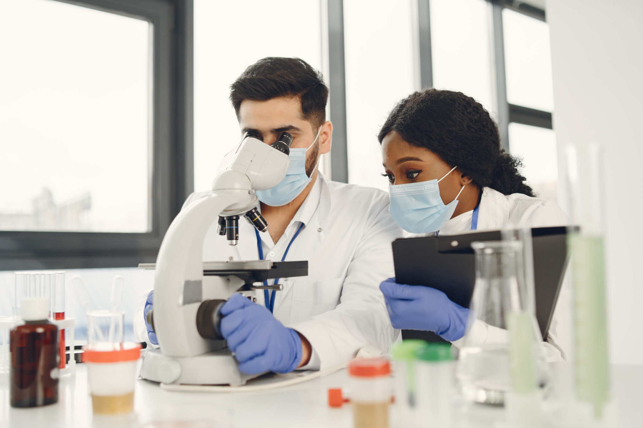 New test. Concentrated skilled researchers wearing uniform. Doing test, creating vaccine.